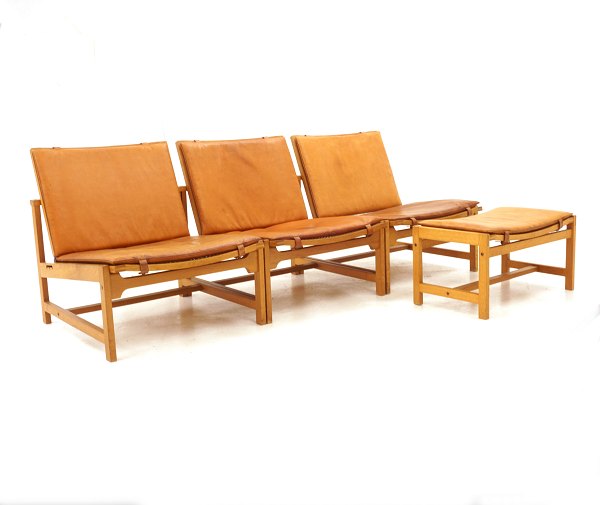Arne Karlsen & Peter Hjort: Set of 3 lounge chairs and 1 stool, oak with 
leather. Danish Design. Presented in Milano 1961. L: 180cm. D: 70cm. Hs: 30cm. 
H: 66cm