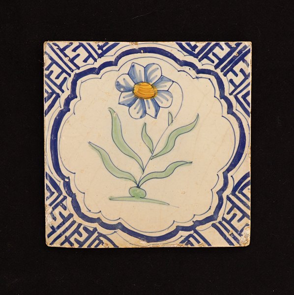 Polykrom dekoreret flise med motiv i form af blomst. Holland ca. år 1620-40. 13x13cm