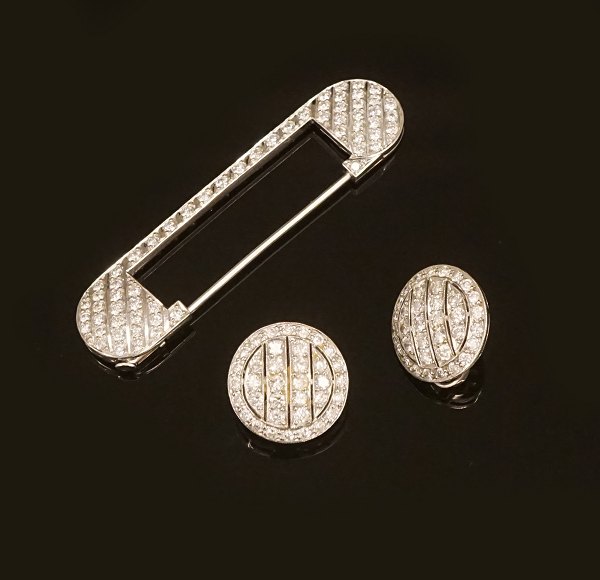Smykkesæt bestående af broche og to øreclips i platin prydet med talrige diamanter. Broche L: 6cm.