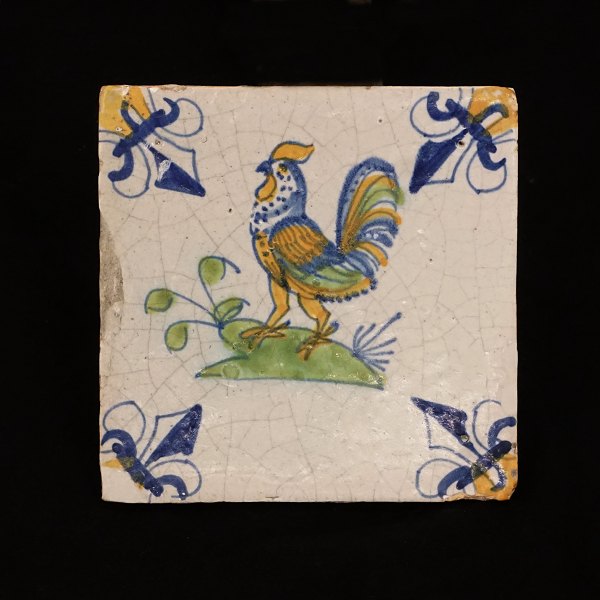Polykromdekoreret flise med motiv i form af hane. Holland ca. år 1640. Mål: 13x13cm